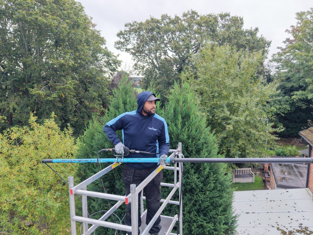 TripleTouch operative using a roof cleaning pole from an access tower
