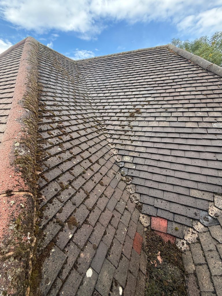 Tiled roof valley covered in moss before cleaning