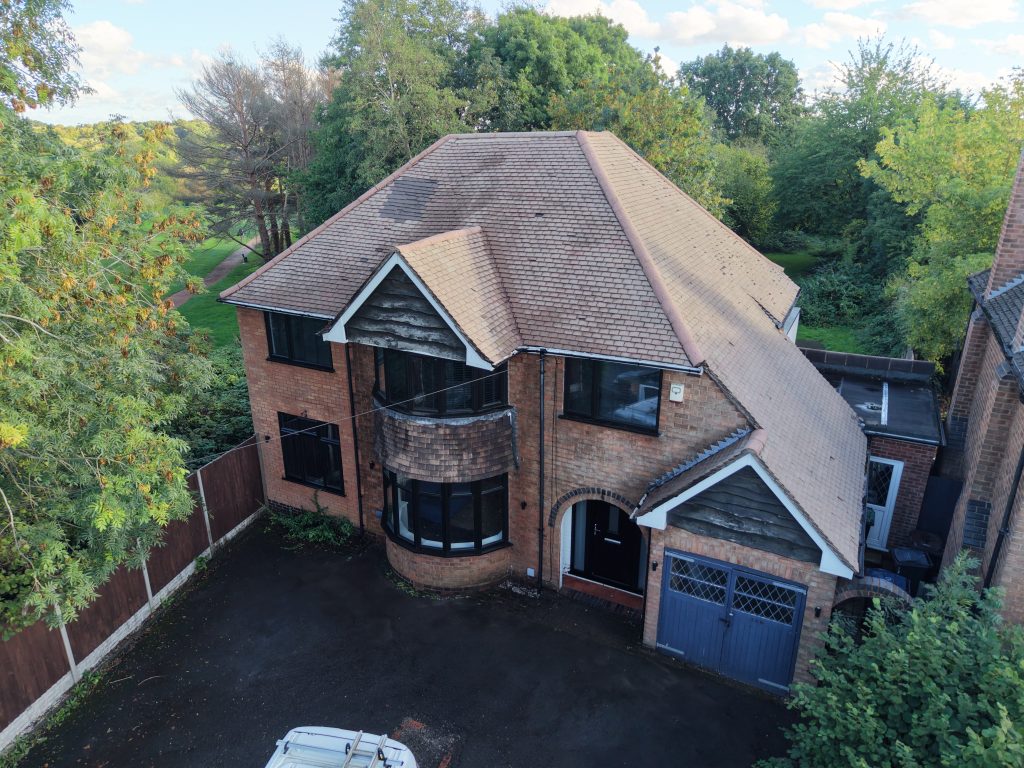 Aerial view of a detached home with a cleaned tiled roof